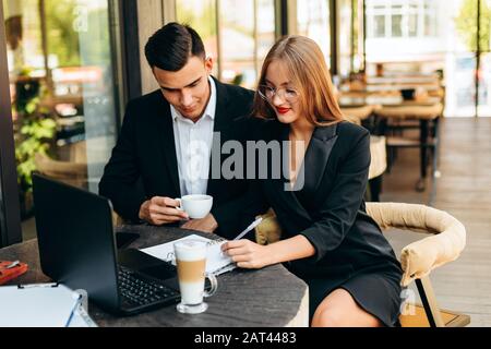 Ein Paar im Café, das während des Abendessens am Laptop arbeitet.- Bild Stockfoto