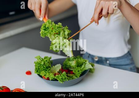 Nahaufnahme mit Salat. Weibliche Hände, die Salat mischen Stockfoto