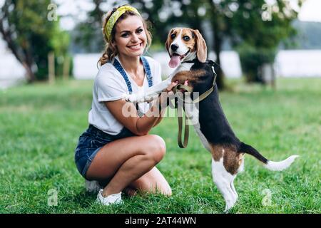 Glückliche Frau, die mit Hund spielt und die Kamera betrachtet. -Bild Stockfoto
