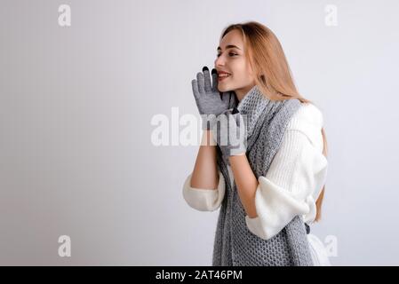 Schöne, glückliche Frau, die jemanden auf grauem Hintergrund anruft Stockfoto