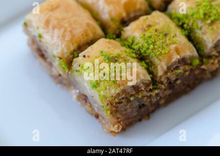 Türkisches Baklava mit Walnüssen und Pistazien auf der weißen Platte, Nahaufnahme. Stockfoto