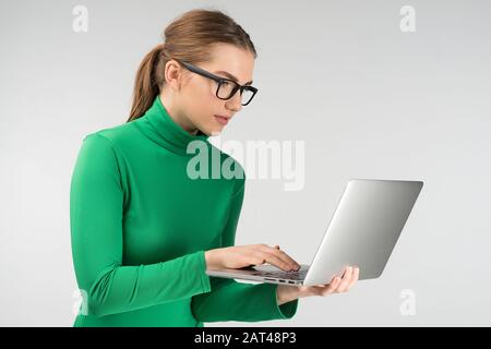 Frau im Profil arbeitet im stehen auf einem Tablet. Betrachten Sie den Bildschirm sorgfältig Stockfoto