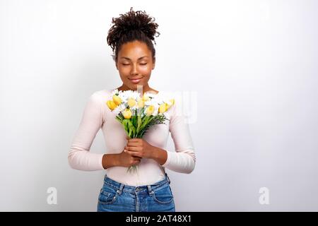 Halblanges Studio-Porträt eines wunderbaren Mädchens mit Blumenstrauß aus Tulpen und Gänseblümchen in ihren Händen Stockfoto