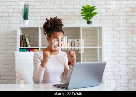 Fröhliche schreie der afroamerikanischen Frau machen eine Gewinner-Geste mit geklischten Fäusten Stockfoto