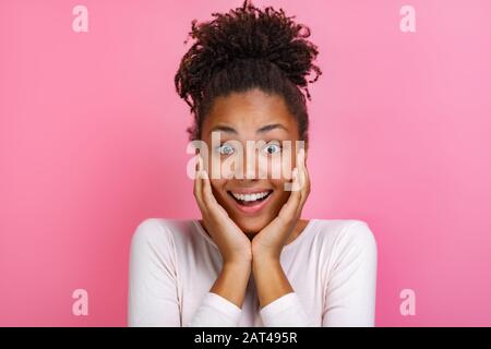 Nahaufnahme des Porträts eines hübschen Mulattopädchens über rosafarbenem Hintergrund mit verblüffter Emotion im Gesicht - Bild Stockfoto