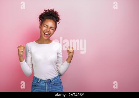 Aufgeregte Frau macht sich im Studio mit eingeklatschten Fäusten in Gewinnergeste die Hände. Konzeptgestus - Bild Stockfoto