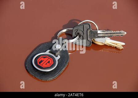 Schlüssel für MG Sportwagen auf Schlüsselring mit fob und MG-Logo, auf der Motorhaube des russet braunen MGB GT Stockfoto