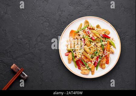 Hähnchenchop Suey in weißer Platte mit schwarzem Schieferhintergrund. Chop Suey ist ein Gericht der amerikanischen chinesischen Küche mit verschiedenen Rührgemüse, Hühnchen m Stockfoto