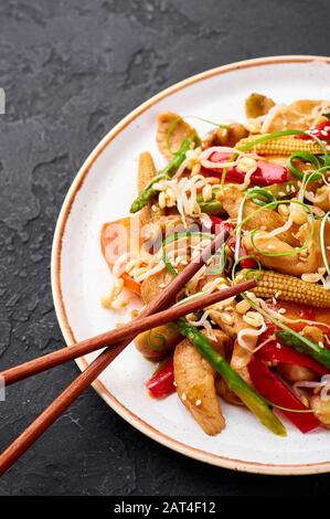 Hähnchenchop Suey in weißer Platte mit schwarzem Schieferhintergrund. Chop Suey ist ein Gericht der amerikanischen chinesischen Küche mit verschiedenen Rührgemüse, Hühnchen m Stockfoto