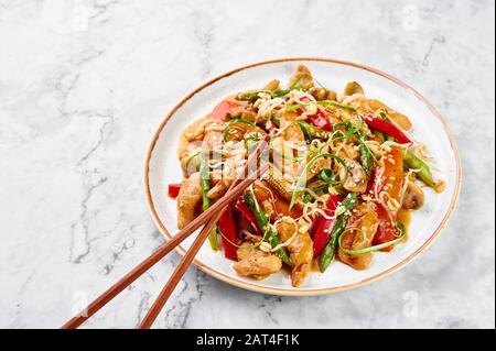 Hähnchenchop Suey in weißer Platte auf Marmorhintergrund. Chop Suey ist ein amerikanisches chinesisches Gericht mit verschiedenen Rührgemüse, Hühnerfleisch a Stockfoto