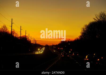 Autos steckten bei dramatischem Sonnenuntergang im Verkehr Stockfoto