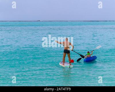 Vater und Sohn genießen Wassersport auf den Malediven. Vater paddleboarding und das Kind Kajak von einer Insel im South Ari Atoll Stockfoto