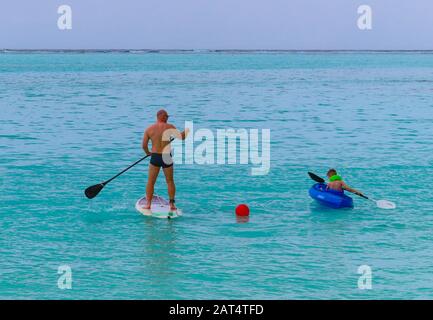 Vater und Sohn genießen Wassersport auf den Malediven. Vater paddleboarding und das Kind Kajak von einer Insel im South Ari Atoll Stockfoto