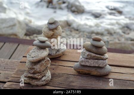 Drei Stapel Zen-Steine auf einem Holzboden am sandigen Strand des Atlantiks. Strand von Gondarém, Porto, Portugal. Stockfoto