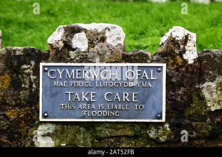 Melden Sie sich in walisischer und englischer Sprache an und warnen Sie vor Überflutungsgefahr an der Wand des Parkplatzes für Ogmore Castle, South Glamorgan, Wales, Großbritannien Stockfoto