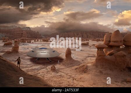 Ein Wanderer entdeckt mit einem Außerirdischen ein gelandeten UFO in der Wüste. Stockfoto