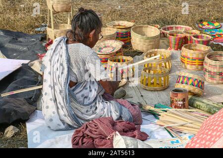 Alte Frau, die Bambusrohrstränge zerflattern lässt, um Körbe für einen Lebensunterhalt in einem Dorf in Bolpur, Westbengalen, Indien, zu verkaufen Stockfoto