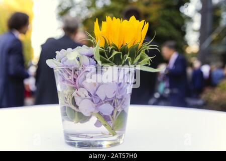Selektive Fokus Aufnahme von bunten Blumen in einer Tasse mit Verschwommene Personen im Hintergrund Stockfoto