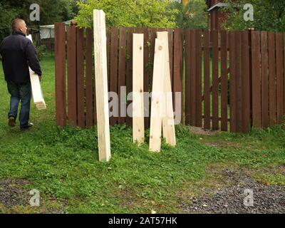 Ein Mann in legerer Kleidung, der geschnittene Bohlen trägt, Außenschuss Stockfoto