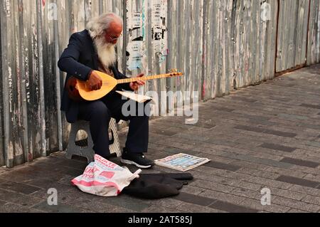 Istanbul, TÜRKEI - 16. September 2019: Ein alter bärtiger Mann, der Musik auf einer traditionellen türkischen Gitarre auf dem Bürgersteig spielt. Stockfoto