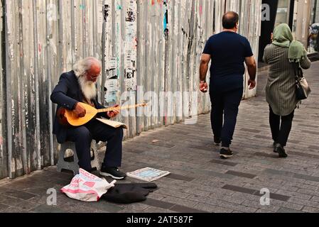 Istanbul, TÜRKEI - 16. September 2019: Ein alter bärtiger Mann, der Musik auf einer traditionellen türkischen Gitarre auf dem Bürgersteig spielt. Stockfoto