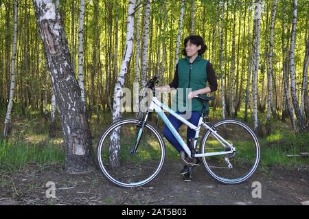 Pinsk, Weißrussland - 05. Mai 2019: Schöne junge Frau Auf einem Fahrrad im Wald vor dem Hintergrund eines Birkenhains. Fitness Stockfoto