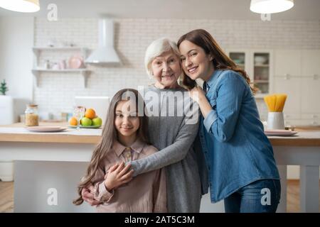 Mutter, Tochter, Großmutter steht umarmend, schön glücklich und gleich. Stockfoto