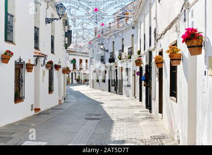 Mijas weiße Straße, kleines berühmtes Dorf in Spanien. Charmante, leere Gassen mit Neujahrsdekorationen, an den Wänden hängen Blumentöpfe Stockfoto