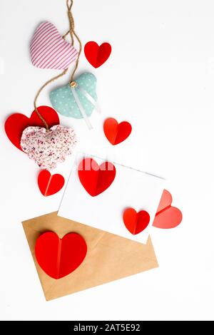 Grußkarte zum Valentinstag. Umschläge auf weißem Hintergrund und rote Kunststoffherzen. Kopierbereich. Stockfoto