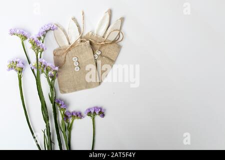 Limonium sinuatum Kristallblau. Schöner, farbenfroher Blumenstrauß mit statizem Blumenstrauß. Geschenkbeutel aus Leinwand mit Knöpfen in Form eines Hasen auf einem Stockfoto
