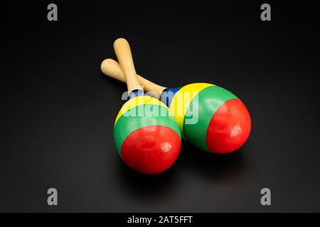 Nahaufnahme eines Paares bunter Maracas, das auf einem schwarzen Untergrund liegt Stockfoto