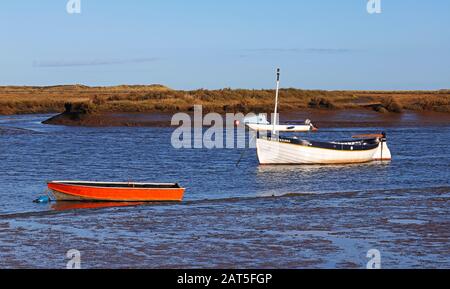 Ein Küstenfischereiboot mit zwei kleineren Booten im Kanal an der Norfolkküste in Burnham Overy Staithe, Norfolk, England, Großbritannien, Europa. Stockfoto