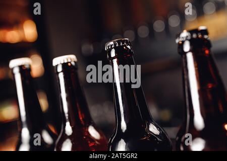 Glasflaschen mit Bier auf dunklem Pub-Hintergrund Stockfoto