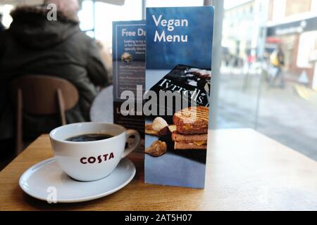 Eine vegane Speisekarte auf einem Tisch in einem Costa Coffeeshop auf einem Hohen St. Die Kette bietet eine Auswahl an Milchprodukten, Snacks und Suppen für Veganer Stockfoto