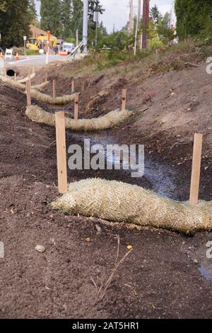 Landabflussarbeiten. Die Verwendung von Strohwatten (Strohwürmer, Biostämme, Strohnudeln). Stockfoto