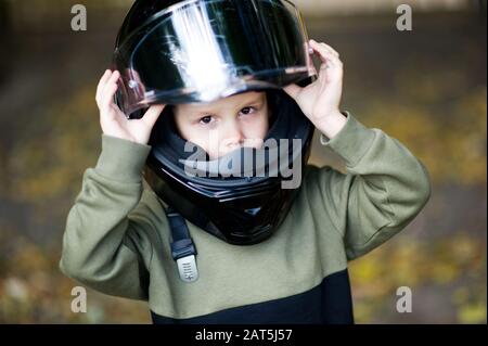 Ein Junge in einem Helm schaut ernsthaft auf die Kamera und stellt seinen Helm ein Stockfoto