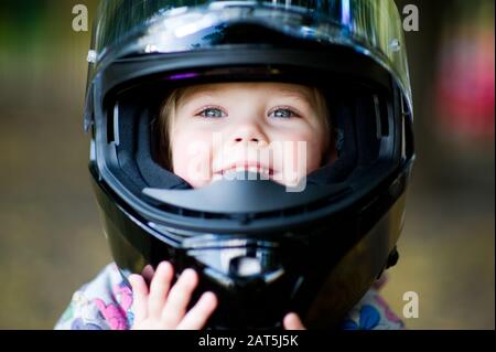 Porträt eines kleinen Mädchens in einem Motorradhelm mit offenem Visier Stockfoto