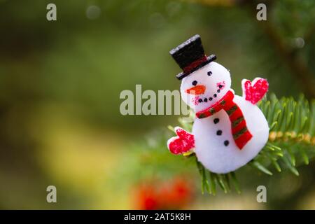 Schneemann, weihnachtsornament, das an einem Kiefernbaum im Freien hängt Stockfoto