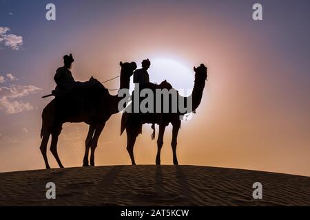 Zwei Männer auf Kamelen in der Thar-Wüste bei Sonnenuntergang, Rajasthan, Indien Stockfoto