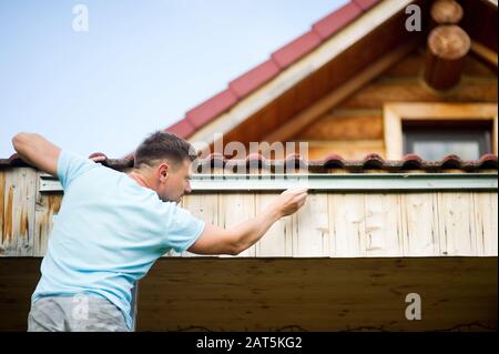 Hausbesitzer repariert an seinem Holzhaus, Blick von hinten Stockfoto