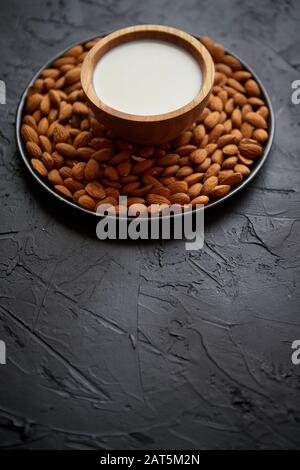 Zusammensetzung von Mandeln, Samen und Milch, auf schwarzem Steingrund. Stockfoto