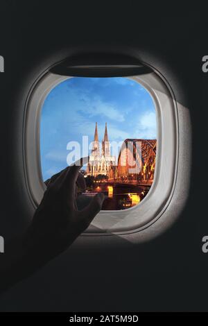 Flugzeugfenster mit einem Luftpanorama von Köln, Deutschland und dem Kölner Dom mit einer Brücke am Abend während eines Fluges Stockfoto