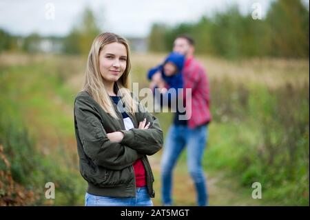 Mutter lächelt, und im Hintergrund spielt ihr Mann mit dem kleinen Sohn. Selektiver Fokus Stockfoto