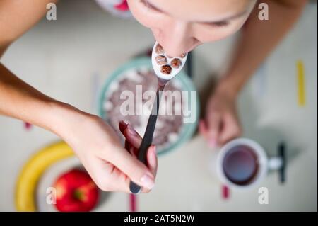 Mädchen, die Schokoladengetreide essen, Draufsicht über den Tisch Stockfoto