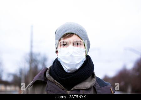 Ein junger Kerl in einer Schutzmaske schützt sich vor Coronavirus, einer Pandemie des chinesischen Virus. Ncov-2019. Stockfoto