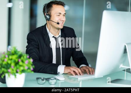 Gutaussehender Geschäftsmann mit Headset, der in seinem Büro interagiert Stockfoto