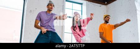 Panorama-Schuss von multikulturellen Männern beim Breakdancing mit attraktivem Mädchen Stockfoto