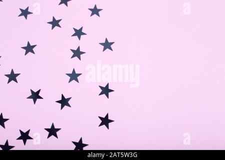 Weihnachtshintergrund mit schwarzen Sternen auf pinkfarbenem Hintergrund. Leerzeichen für Text Stockfoto