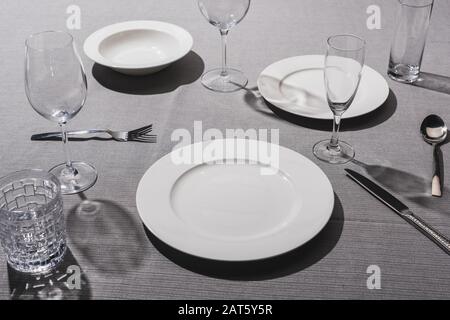 Leeres Geschirr mit Gläsern auf grauem Tuch Stockfoto