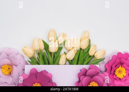 Blick auf Tulpen in violetter Einkaufstasche mit Papierblumen isoliert auf Weiß Stockfoto